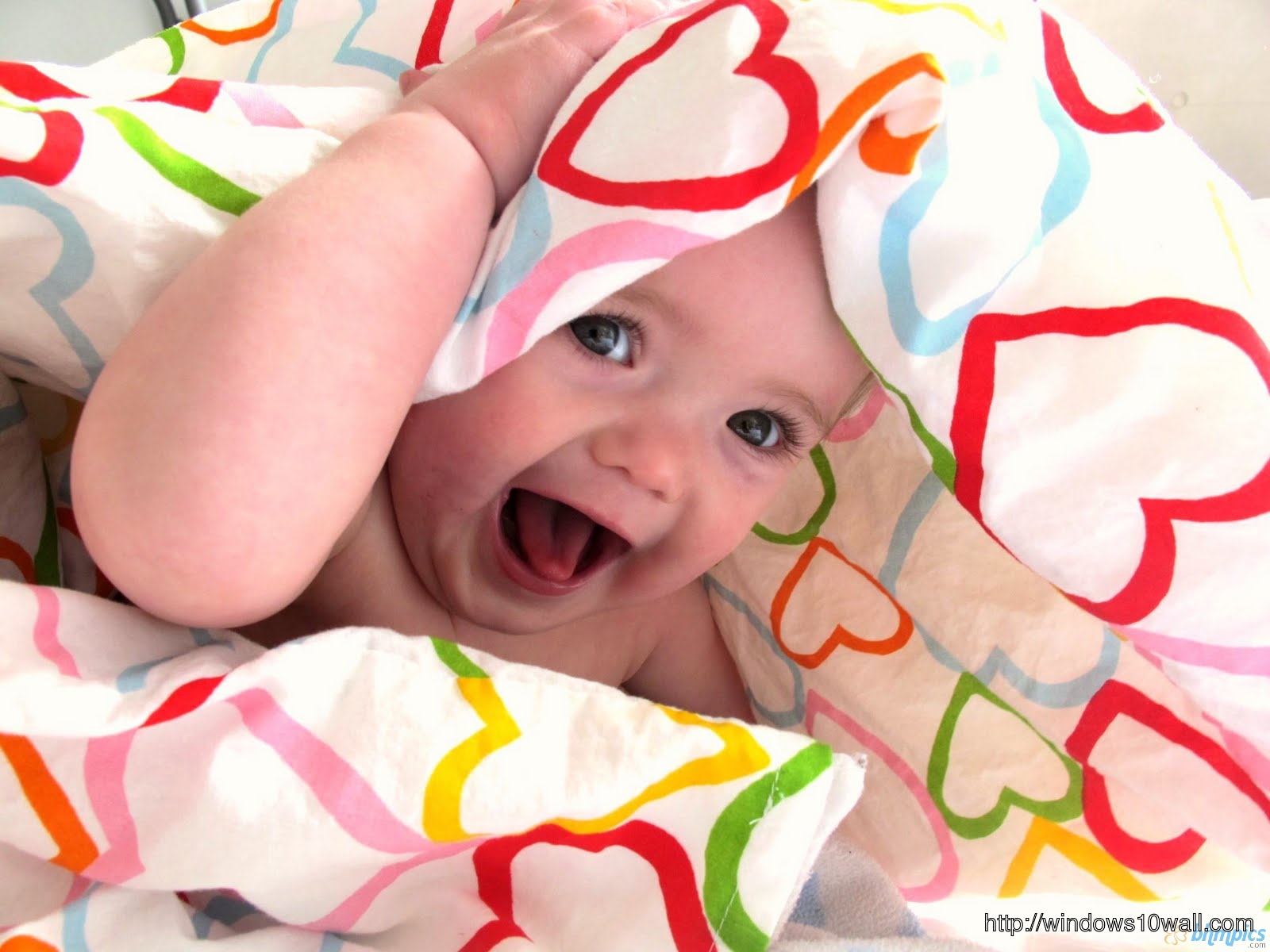 Baby laughing in a bedsheet background wallpaper